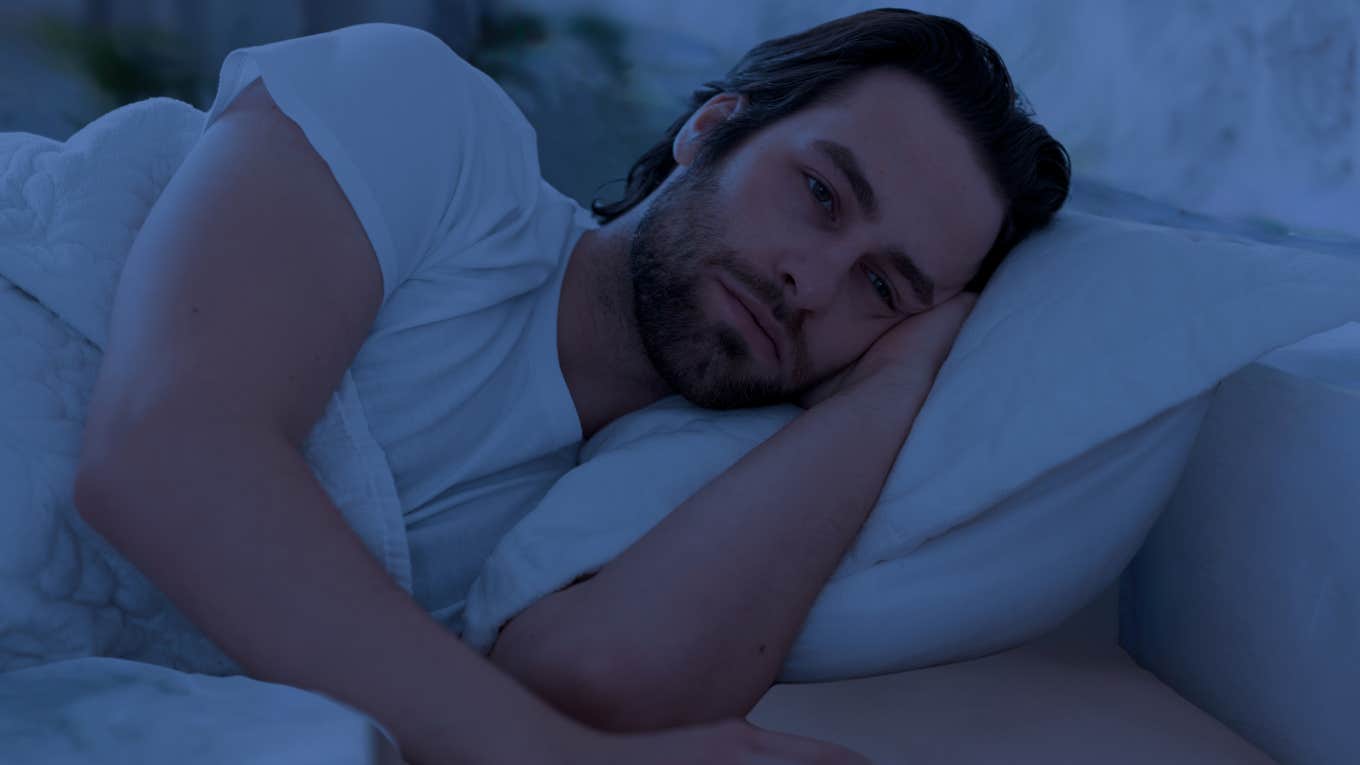 Man laying in bed struggling to fall asleep. 