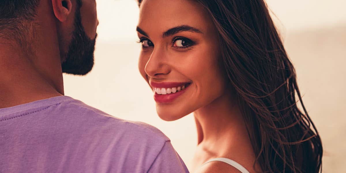 Woman smile and looks over her shoulder next to man.