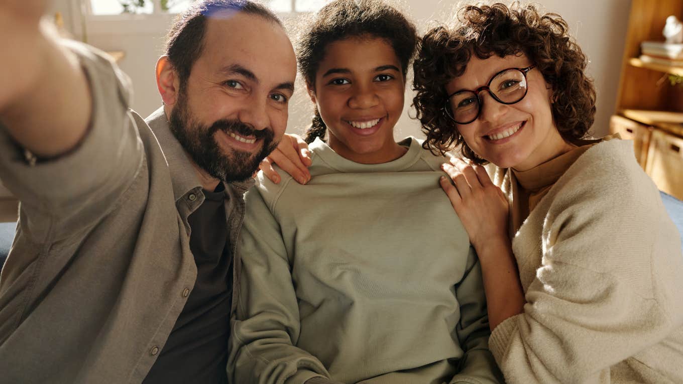 happy family with adopted daughter smiling at camera