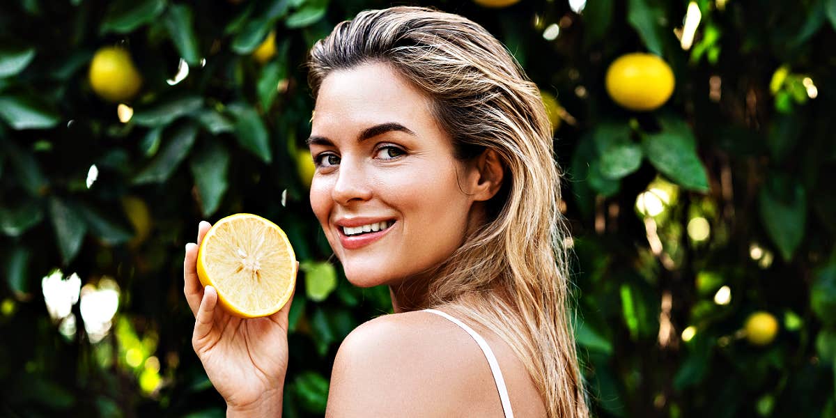 best superfoods to eat as an empath or hip smiling blonde woman holding a lemon in a lemon grove