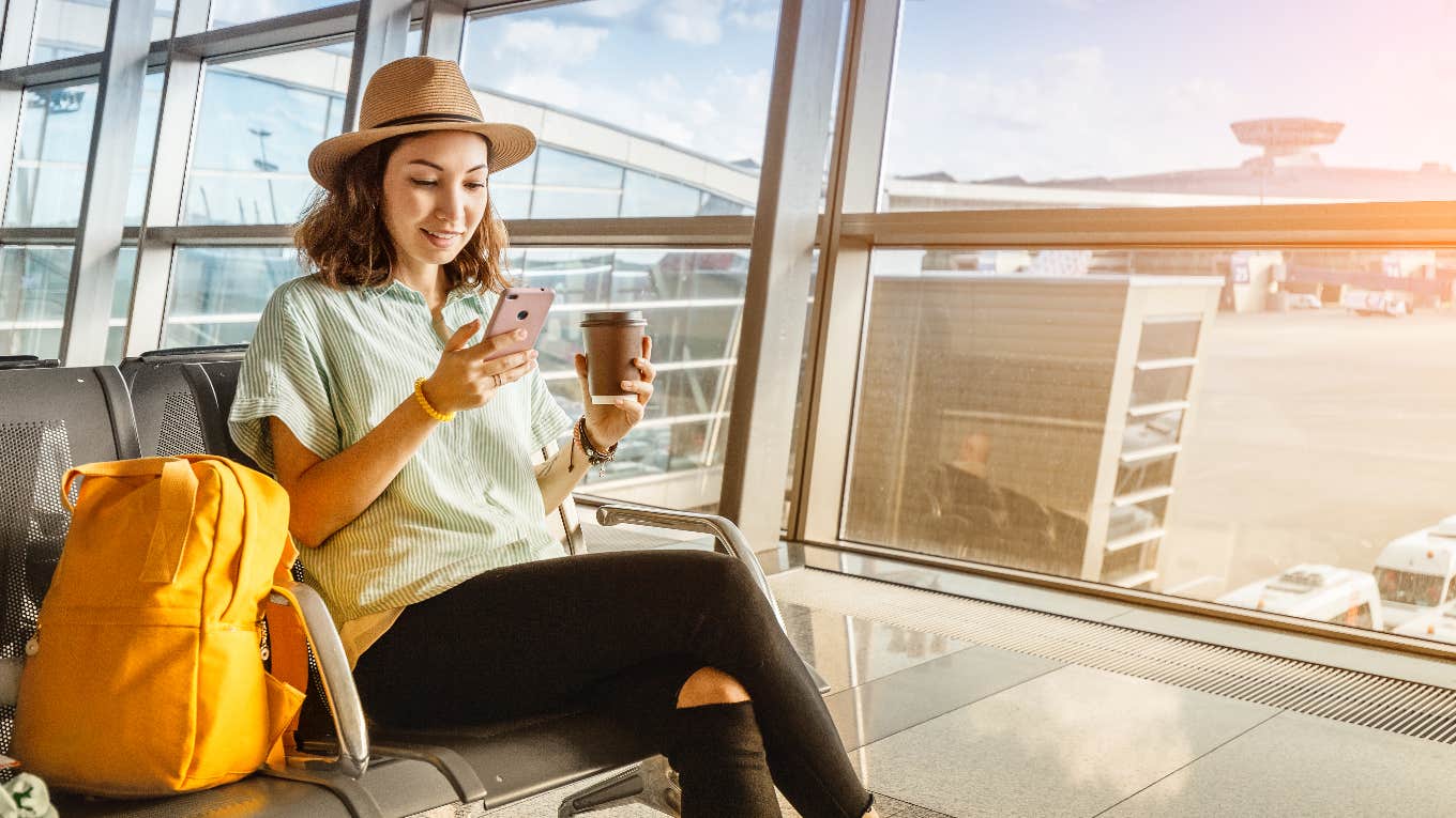 woman at gate using flight hack on phone