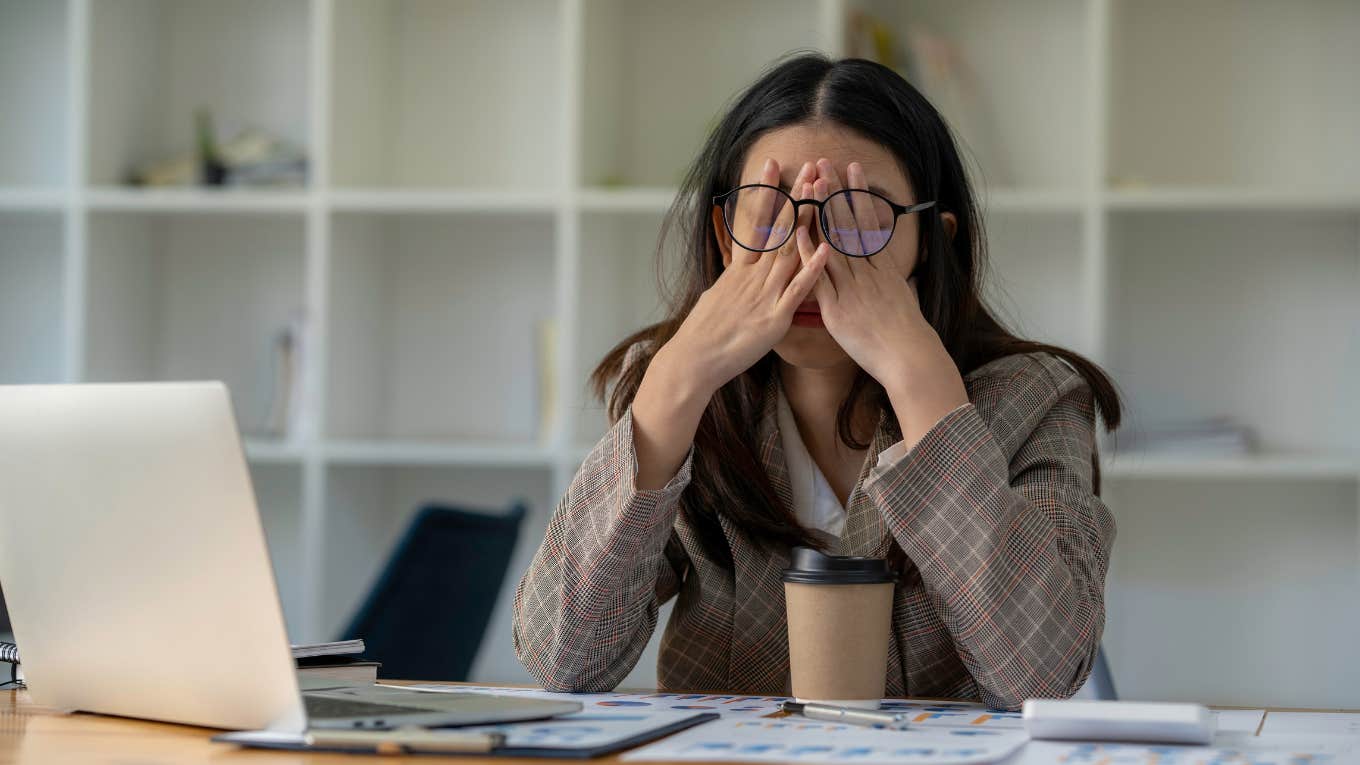 Frustrated employee holds her head in front of computer.