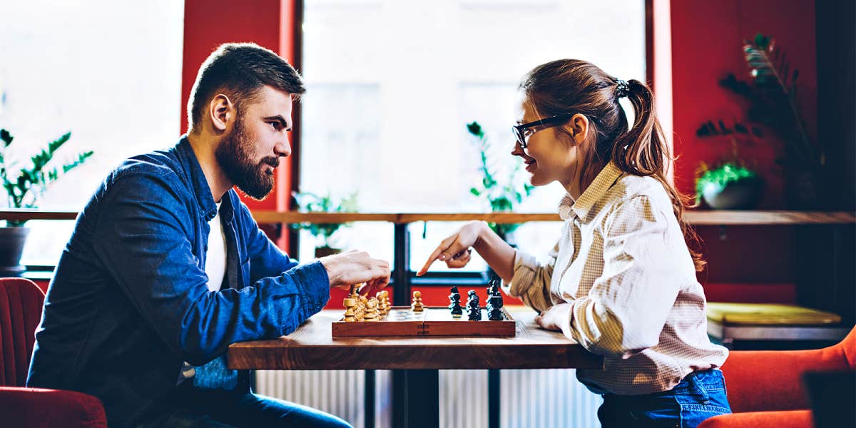 Couple playing chess in a red room with big windows