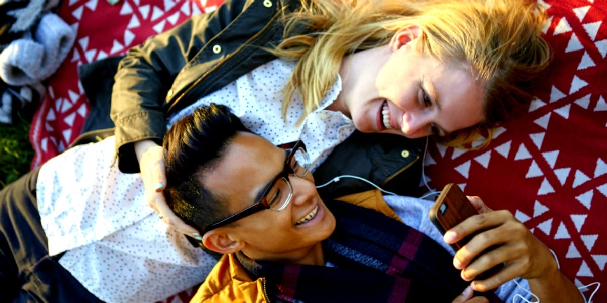 woman and man laying on a picnic blanket laughing