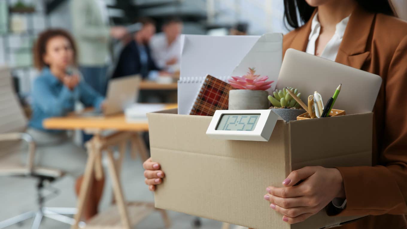 closeup shot of young woman carrying box out of office after quitting