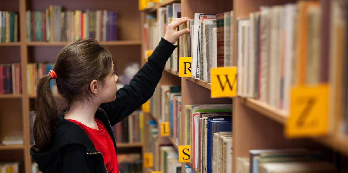 Girl looking for book in school library