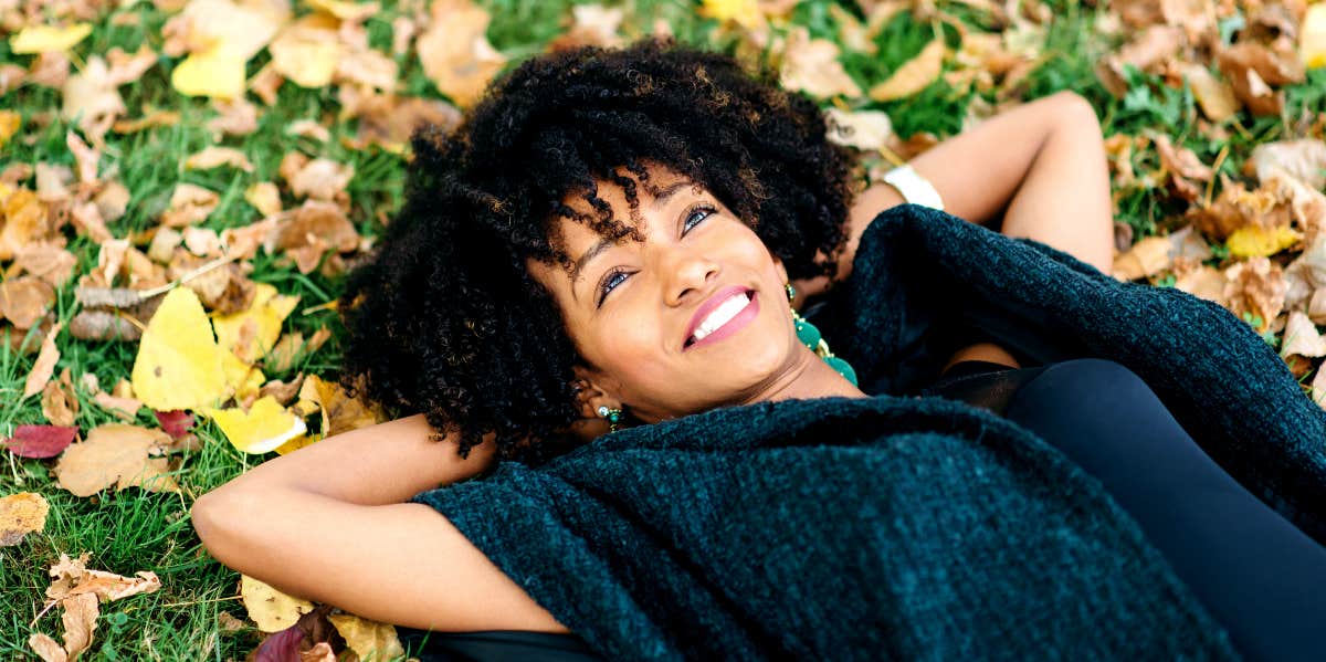 Relaxed, serene woman lies on the grass.