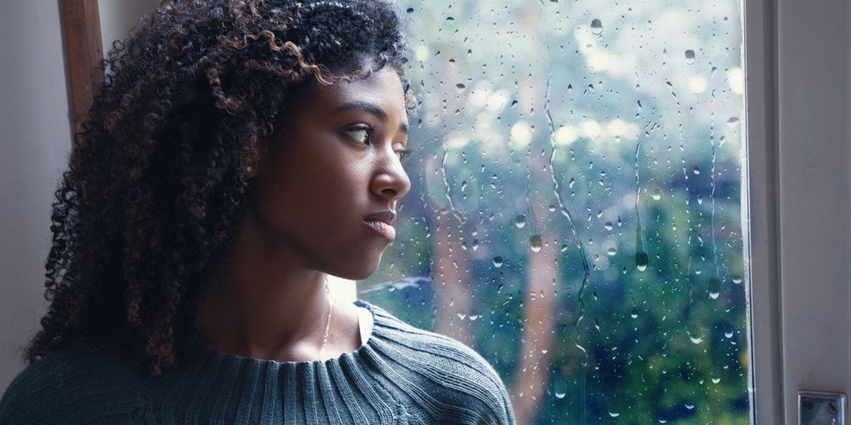 woman looking out window rain