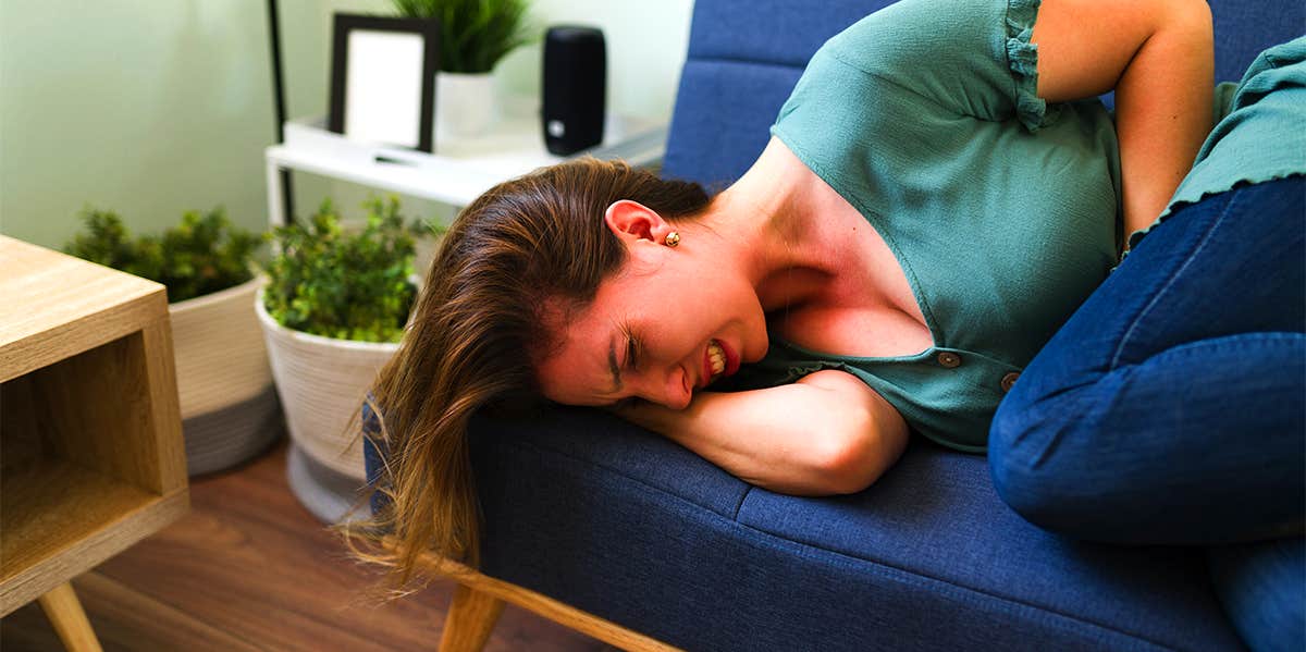 woman with stomach pain laying on couch