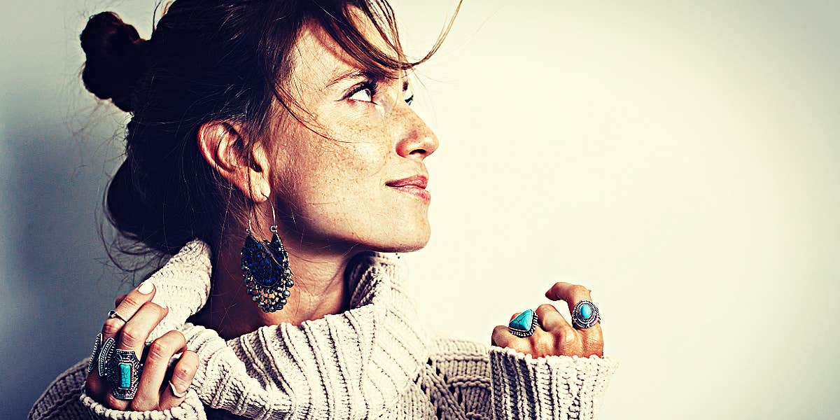 freckled brunette woman looks up, wearing sweater