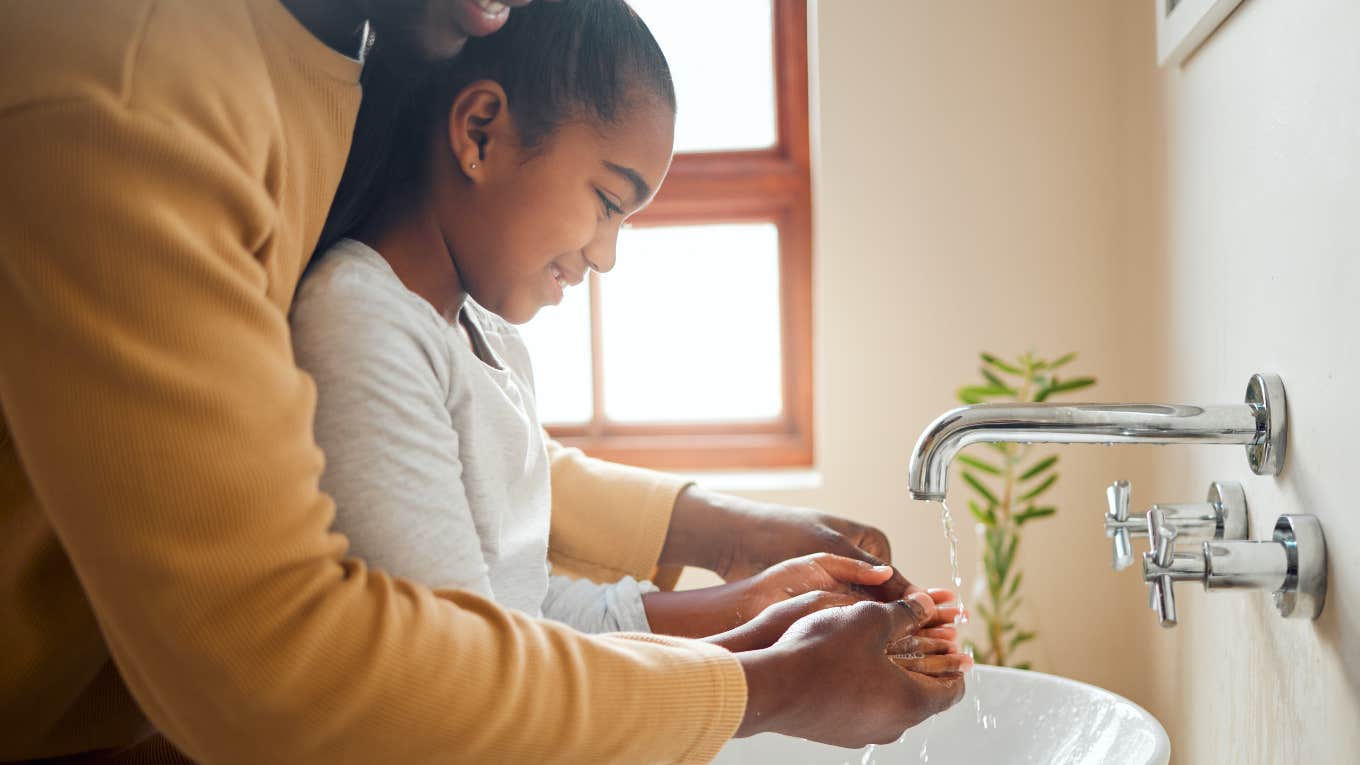 dad helping daughter wash her hands at sink