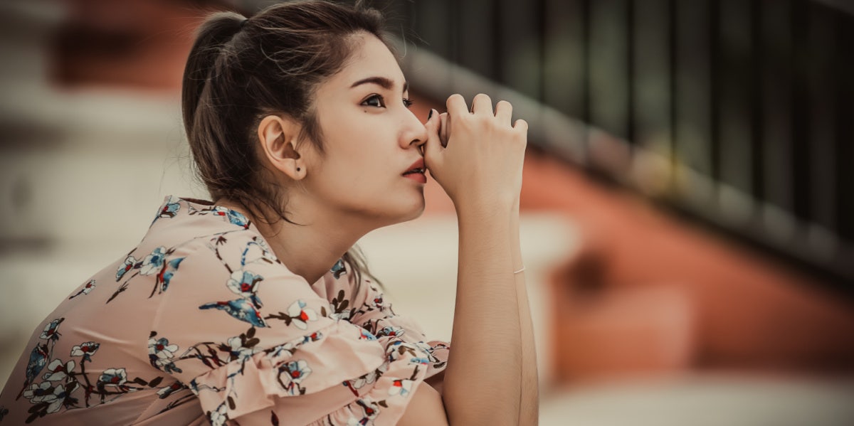 sad woman sitting on steps hands on face