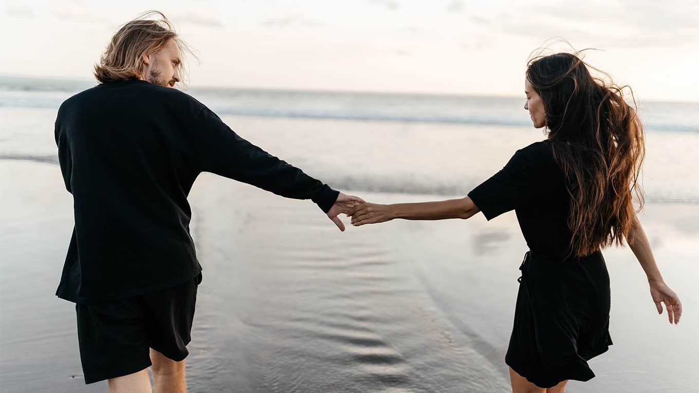 guy and girl holding hands walking on the beach