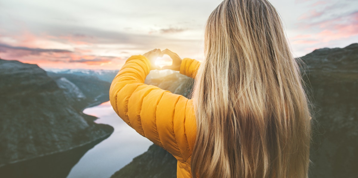 woman making a heart in the sun