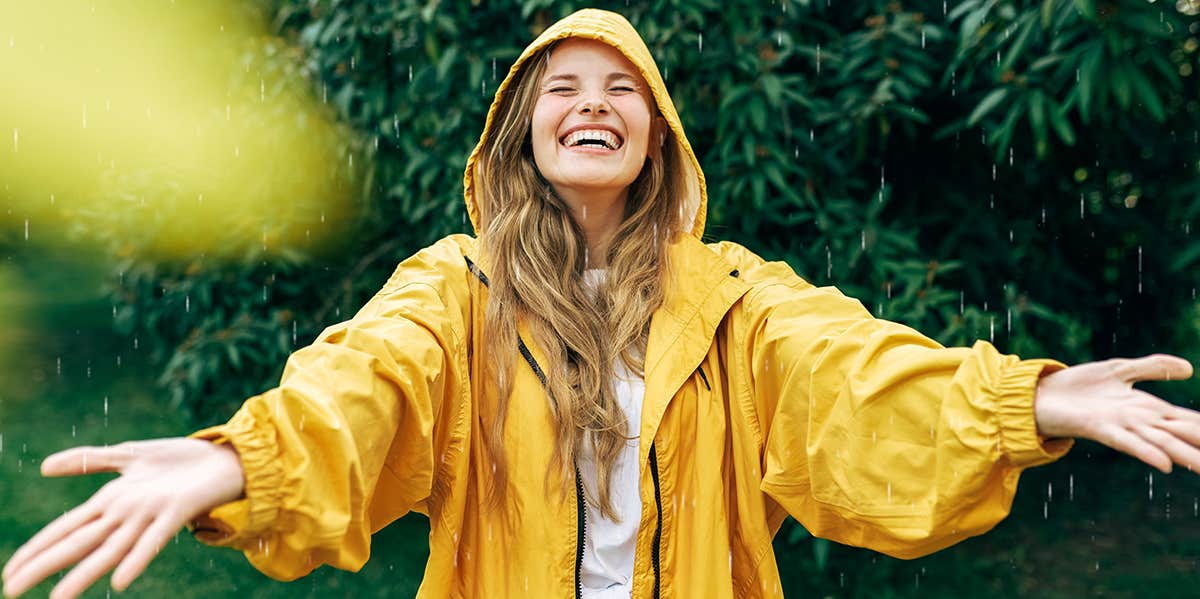 woman smiling in the rain in a yellow raincoat
