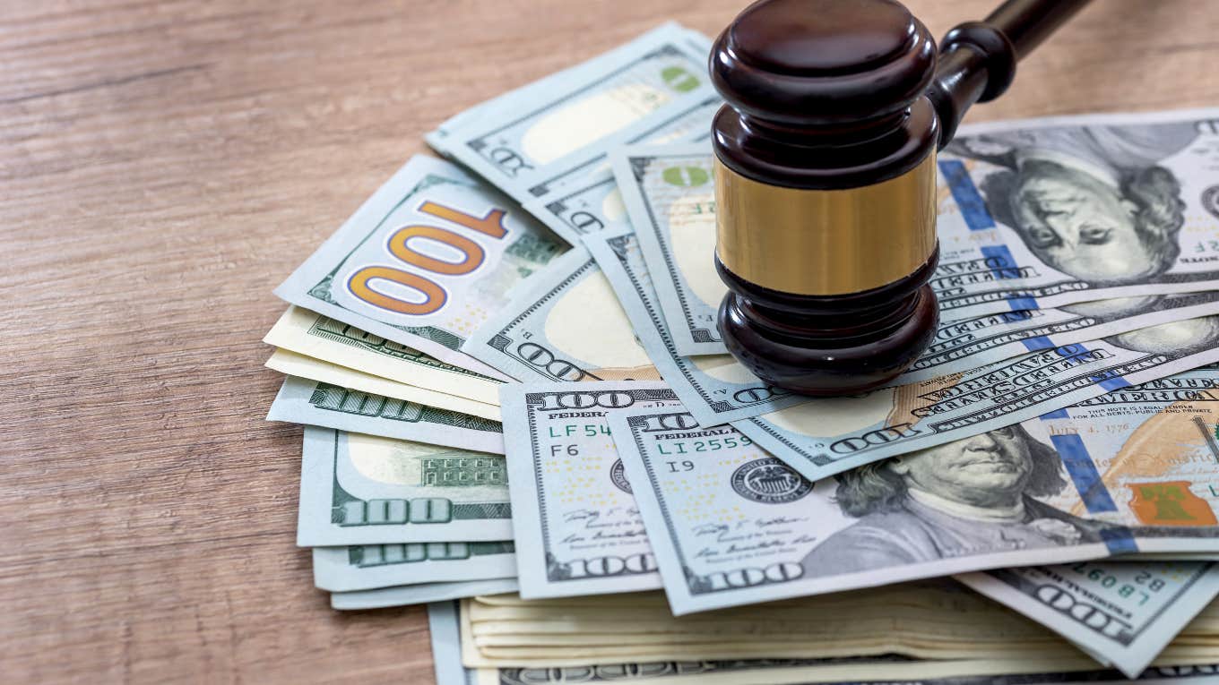 Grandkids Sue After Their Grandpa Only Left Them $64 Each Because They 'Didn't Visit Enough' gavel on top of pile of $100 bills