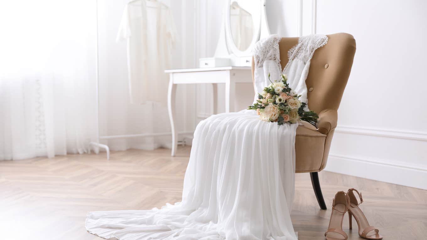 wedding dress and flowers sitting on chair next to shoes