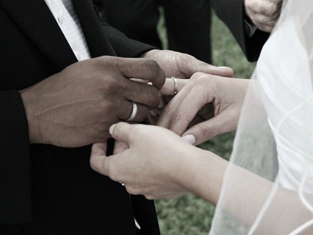 groom putting bride's wedding ring on