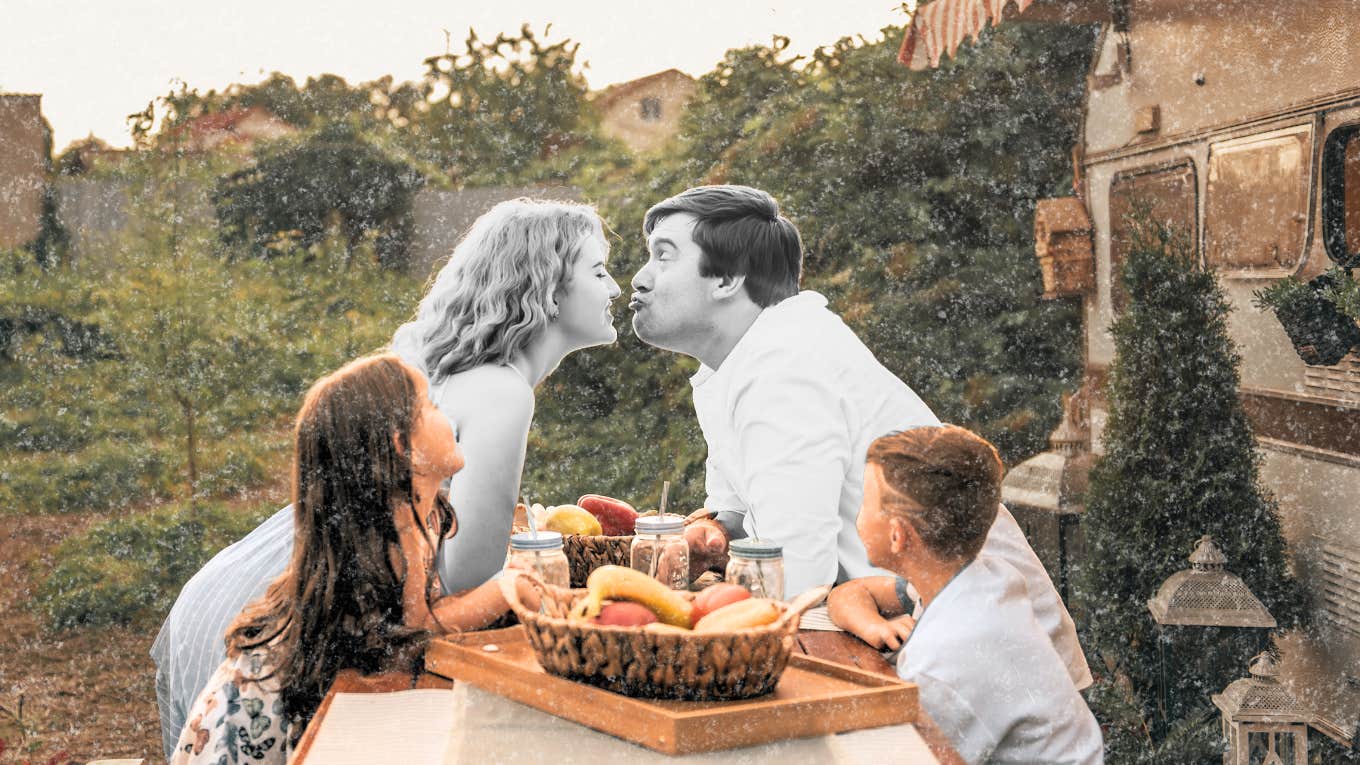 mom and dad sharing a little kiss at dinner table in front of their children