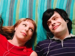 guy and girl laying on blanket listing to headphones