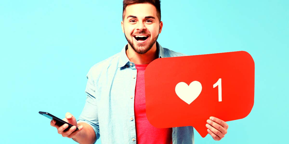 15 Signs Of Guys Who Need Constant Female Attention Man holding cell phone and social media like sign