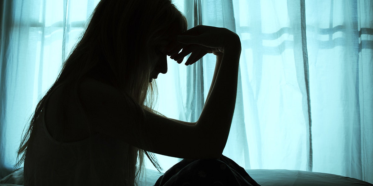 woman in shadow with hand on forehead