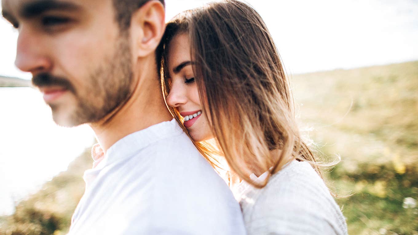 loving couple having fun, cuddling, smiling in a field.