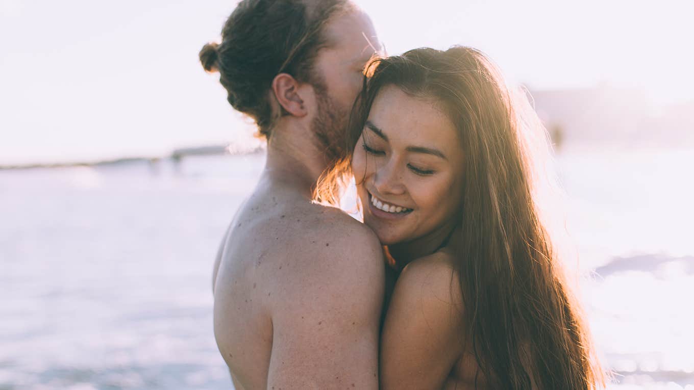 couple is giving each other hug on the beach when is sunset