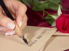 hand holding pen letter writing with red rose