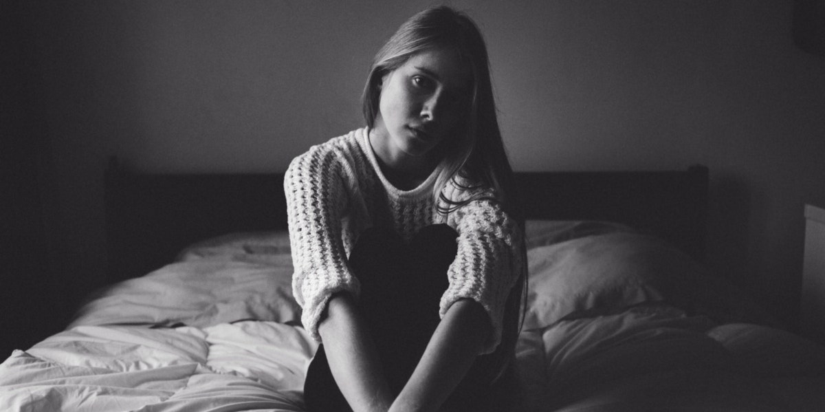 morose woman sitting on top of bed