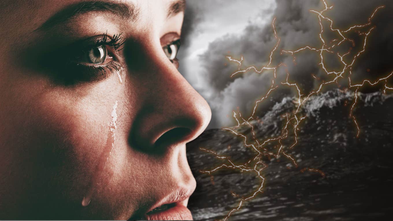 woman staring into a storm with a tear rolling down her cheek