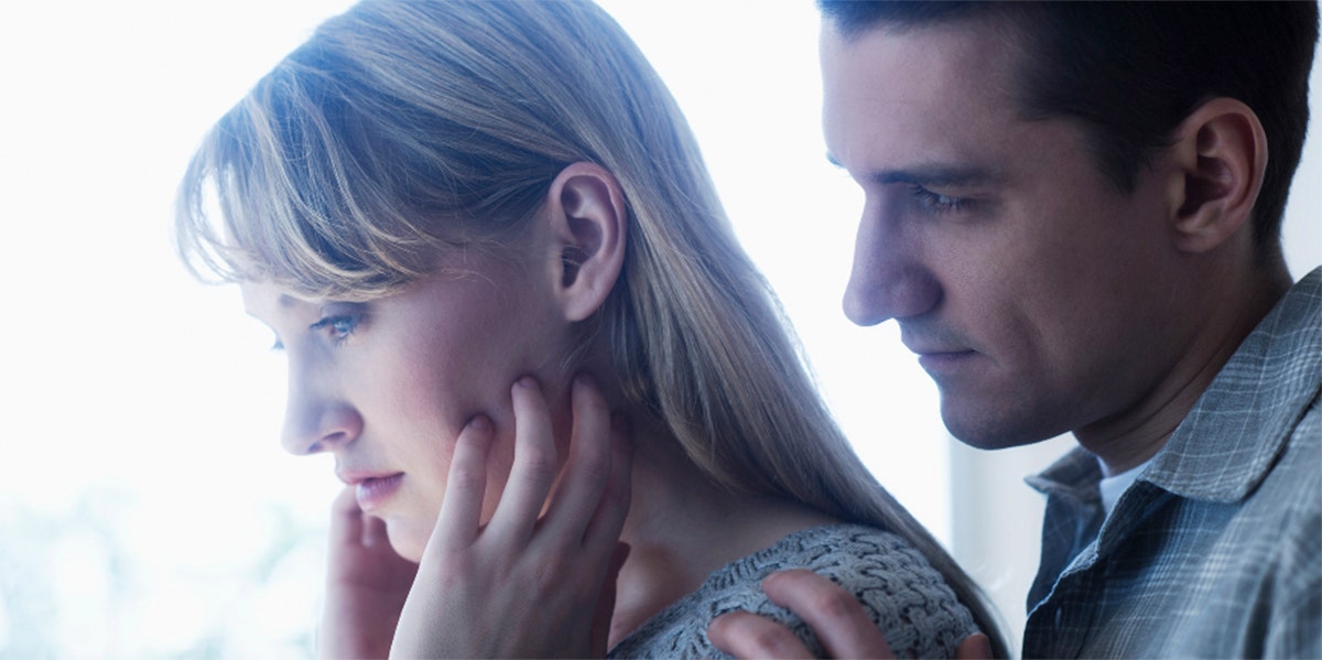 I Deeply Resented My 'Unromantic' Husband — Until This A-Ha Moment woman looking frustrated with husband over her shoulder