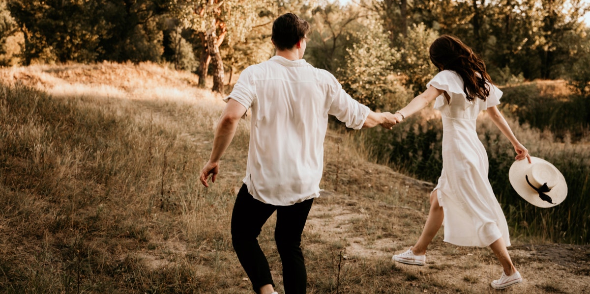 woman and man running in field 