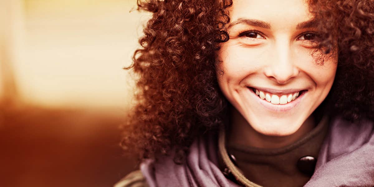 curly-haired woman smiles at the camera