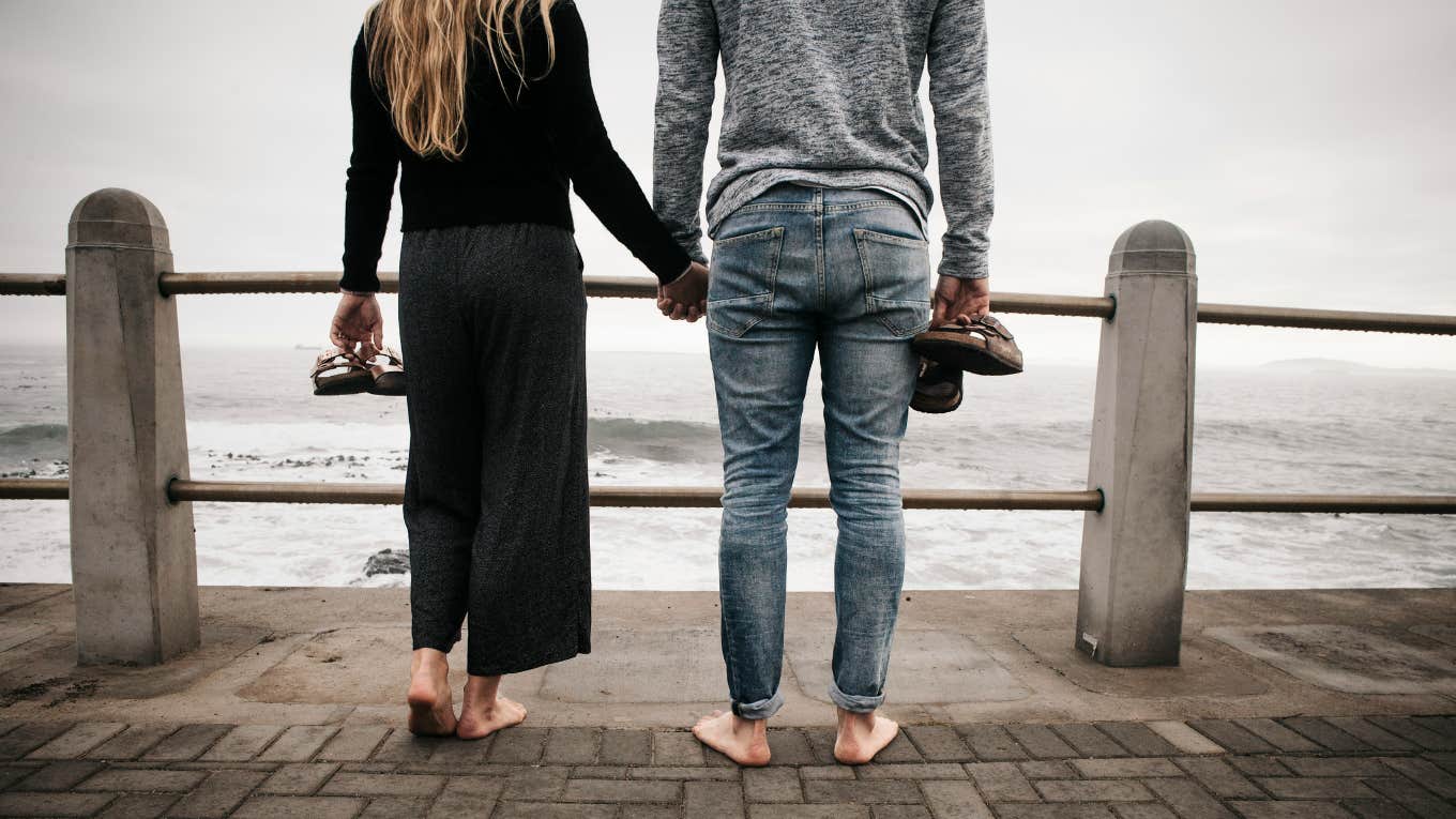 Couple watching turbulent waters, holding hands