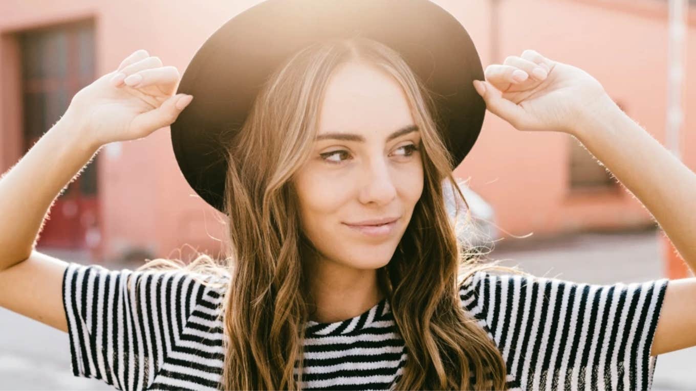 Woman with a healthy attitude, wearing a hat, smiling lightly in the sun