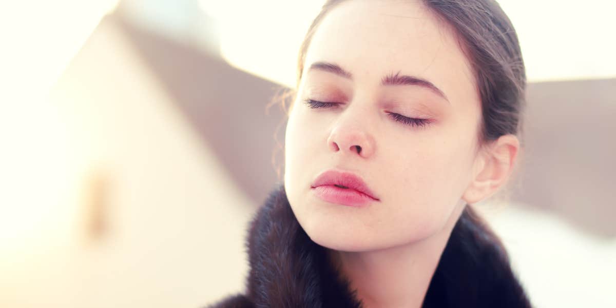 young white woman with brown hair closes her eyes, pensive