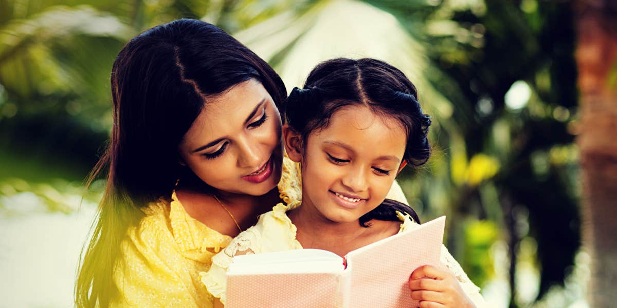 Mom and daughter reading a book outdoors