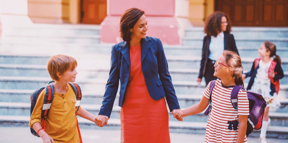 mom holding the hands of two children