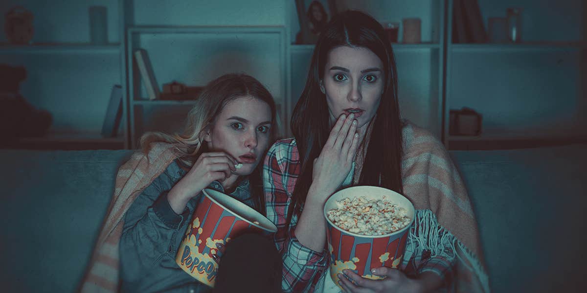 two people holding pop corn , looking scared