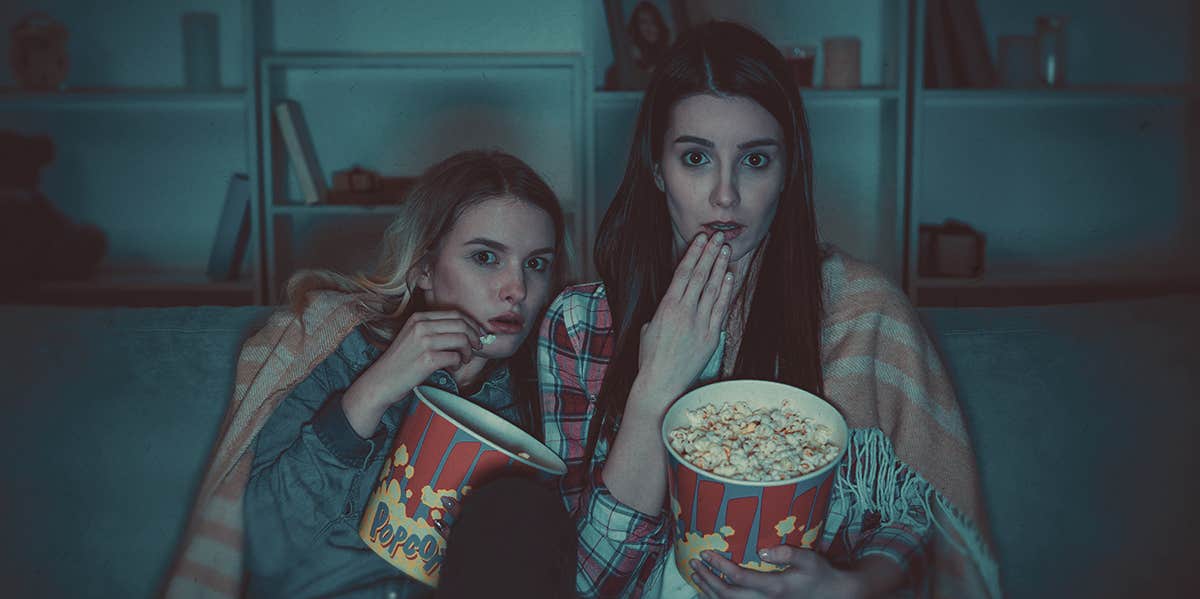 Why Serial Killers & True Crime Stories Are So Fascinating, According To A Psychologist two people holding pop corn , looking scared
