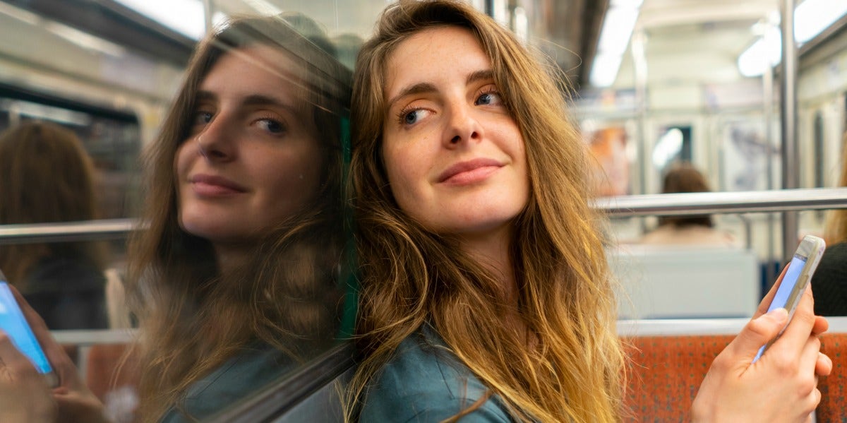 What Does It Mean To Be A Heteroromantic Bisexual? woman smiling on subway holding phone