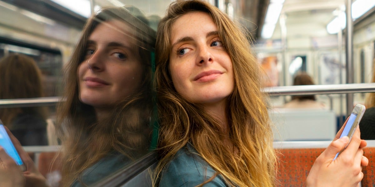 woman smiling on subway holding phone