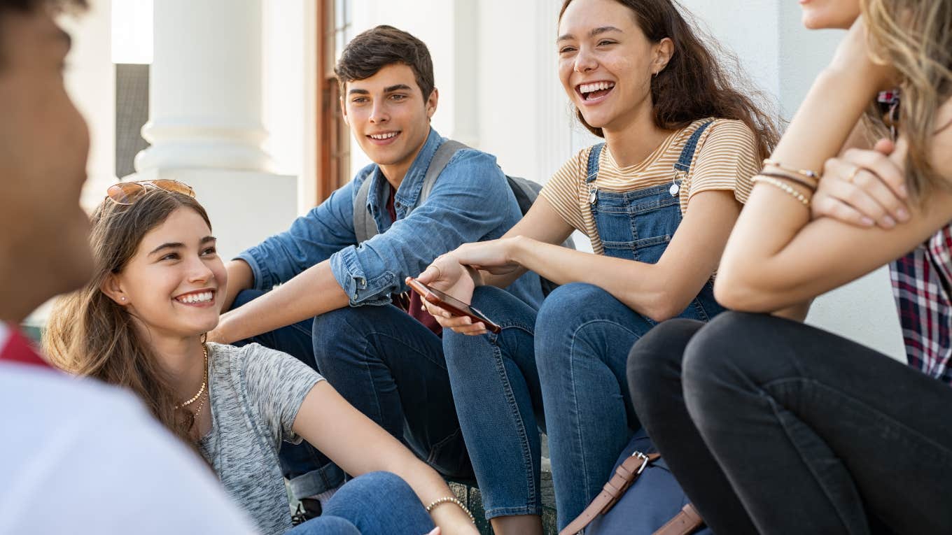 group of high school students sitting and laughing together outside