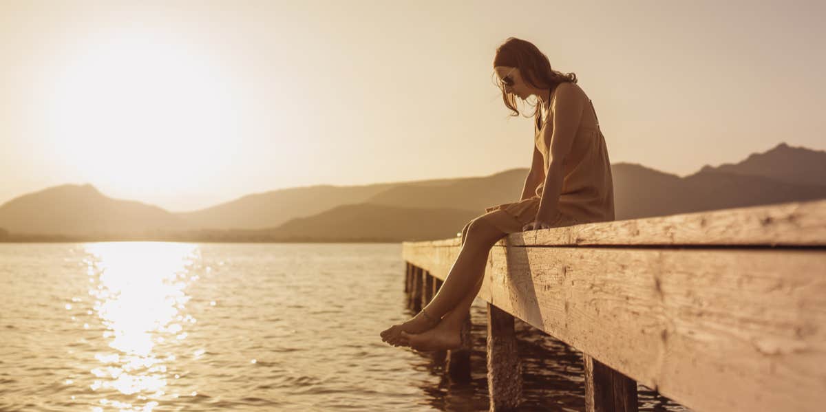 woman sitting on pier by water