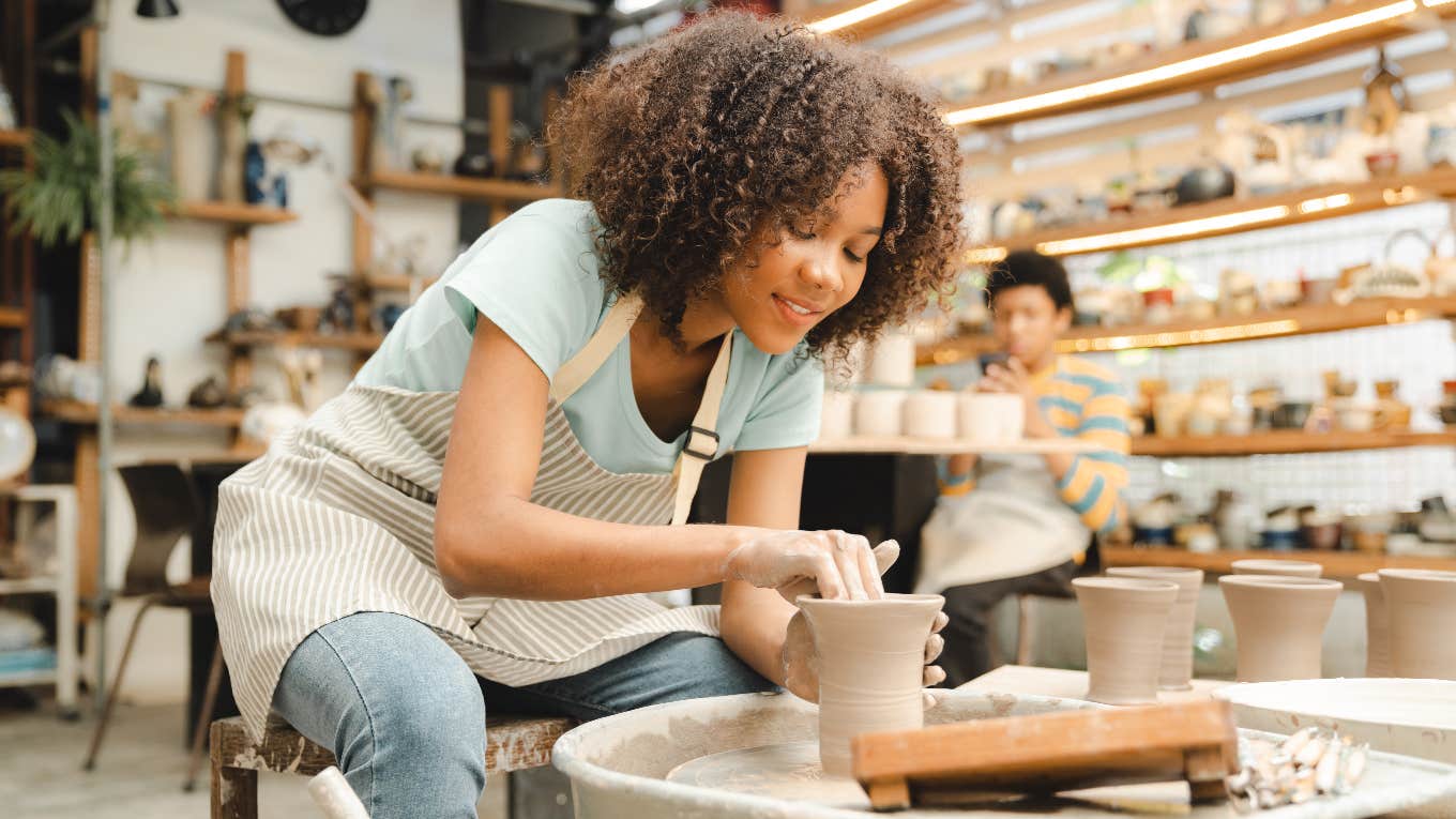 Hobbies Are The Key To A Happier Life, A Therapist Says happy woman doing pottery as a hobby