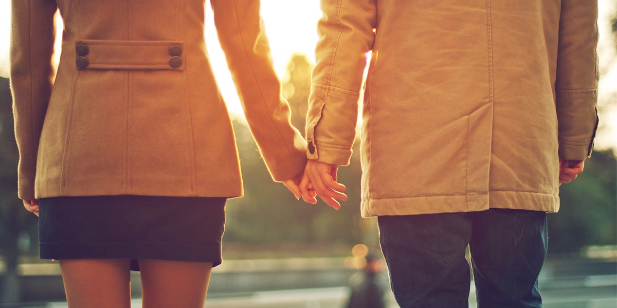 man and woman holding hands in sunset