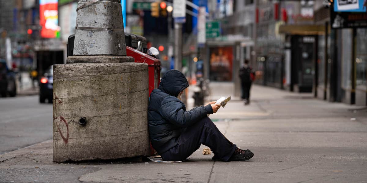 Homeless man reading a book on the street