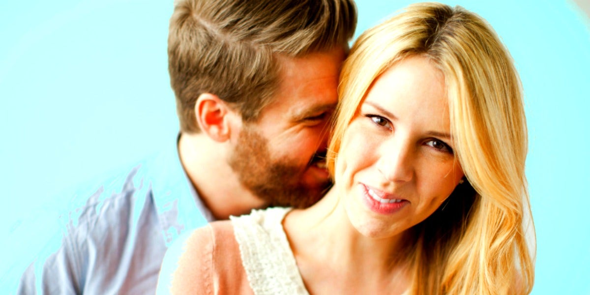 man kissing woman's neck woman smiling blue background