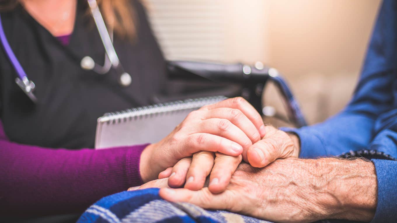 close up image of a nurse holding the hand of an elderly patient